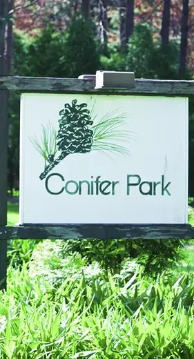 Sign for Conifer Park surrounded by lush greenery at a detox center in Albany.